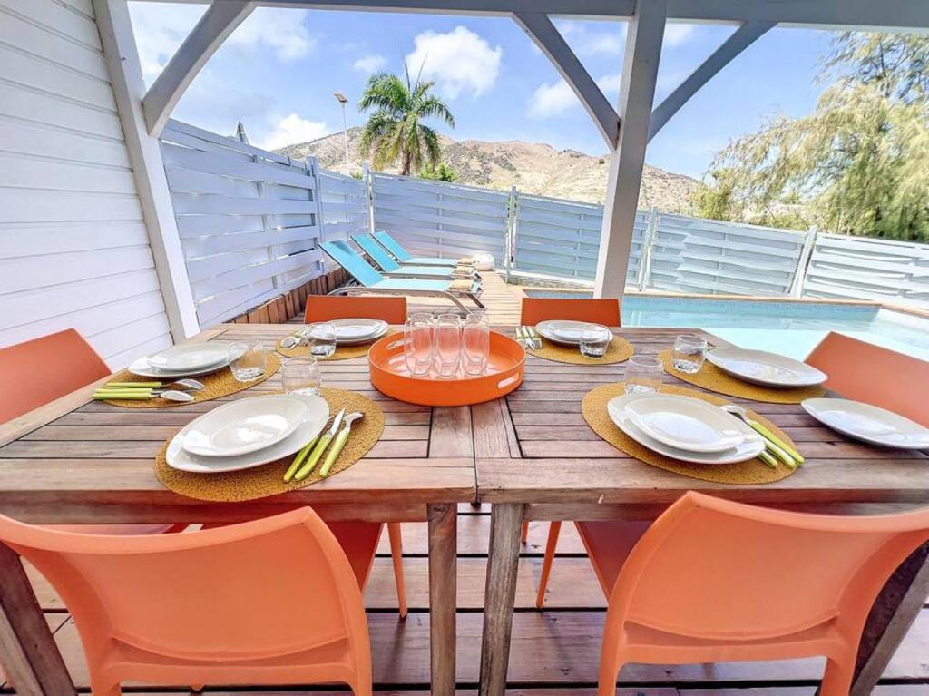 a wooden table with orange chairs and a tableasteryasteryasteryasteryasteryasteryastery at Maison Ti Case, private pool, next to Pinel Island in Cul de Sac