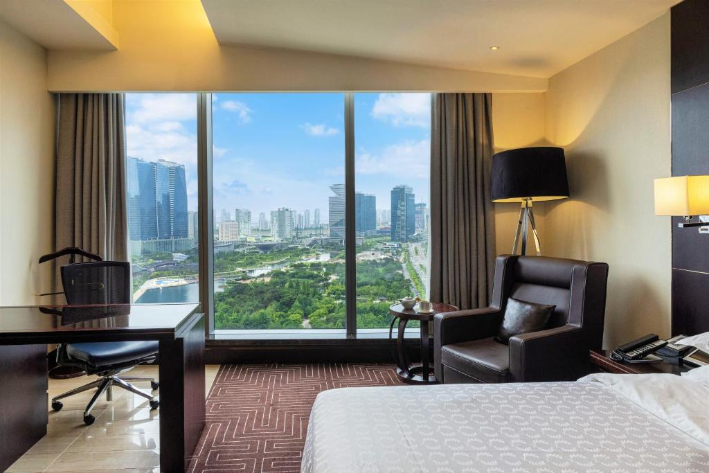 a hotel room with a bed and a desk and a window at Sheraton Grand Incheon Hotel in Incheon