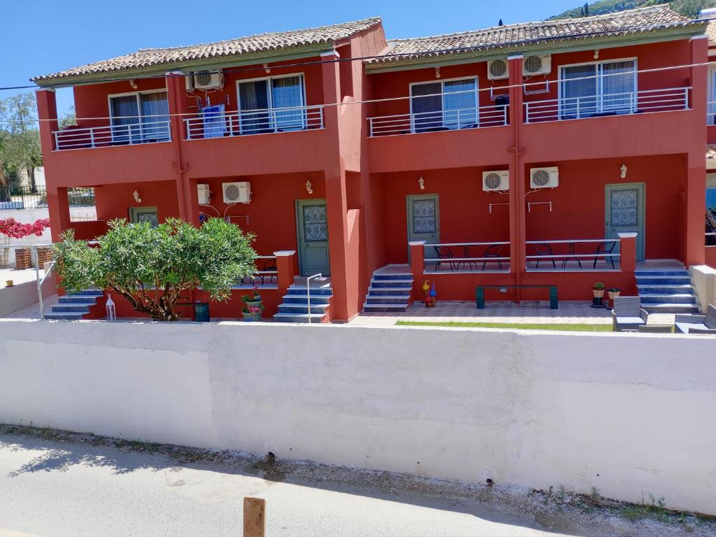 un edificio rojo con bancos delante en maria corfu apartments, en Mesongi
