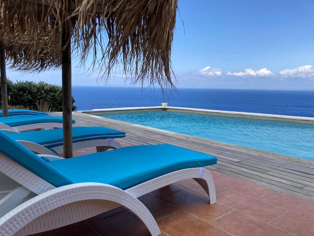 a pool with chairs and a view of the ocean at Apartment at KiVA-villa, Kampi, KEA, Cyclades, Greece in Ligia