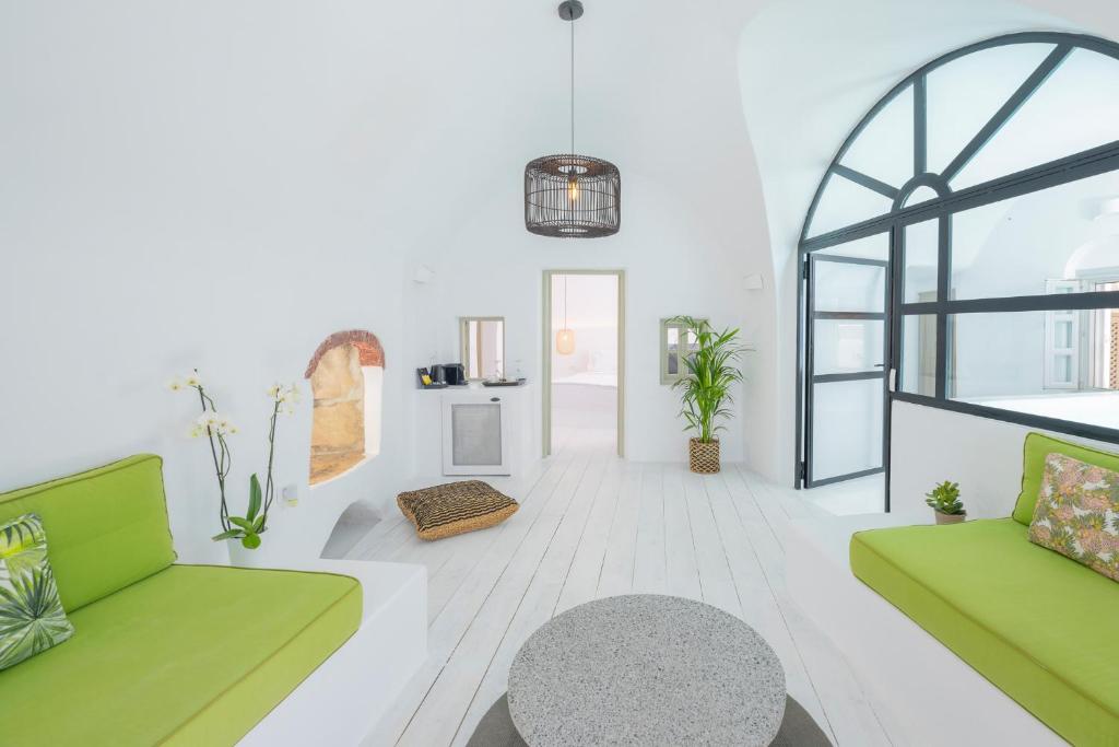 a living room with two green couches and a table at Nano Oia Canaves in Oia