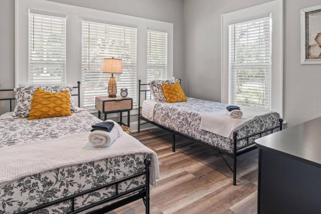 een slaapkamer met 2 bedden, een tafel en 2 ramen bij BeeKeeper's Inn - Beautifully Renovated 1929 Bungalow with 2 Bedrooms on Brick Street near Tampa's Attractions in Tampa