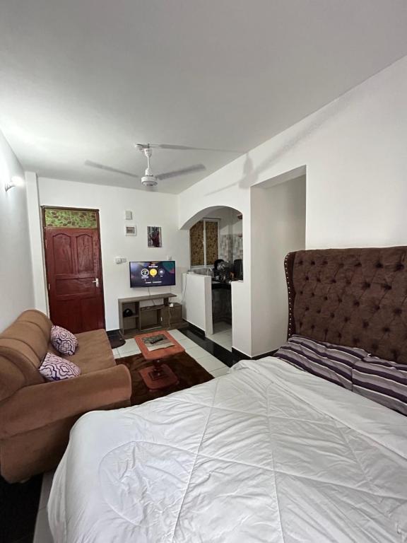 a bedroom with a large bed and a couch at Rainbow apartment in Mombasa