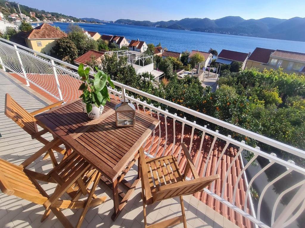 een houten tafel en stoelen op een balkon met uitzicht op het water bij Apartments Klara in Viganj