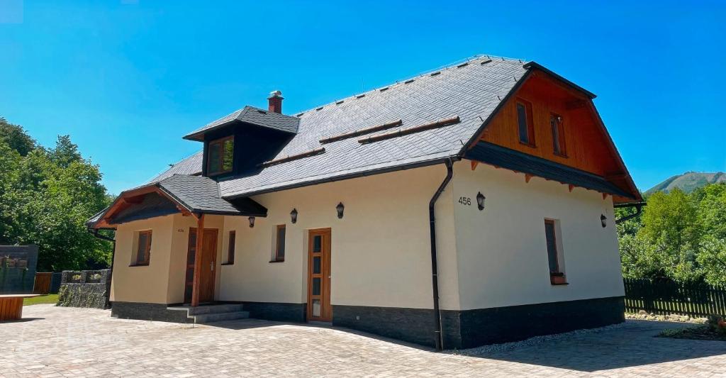 a small white building with a black roof at Ubytování v soukromí s bazénem Tři Splavy in Čeladná