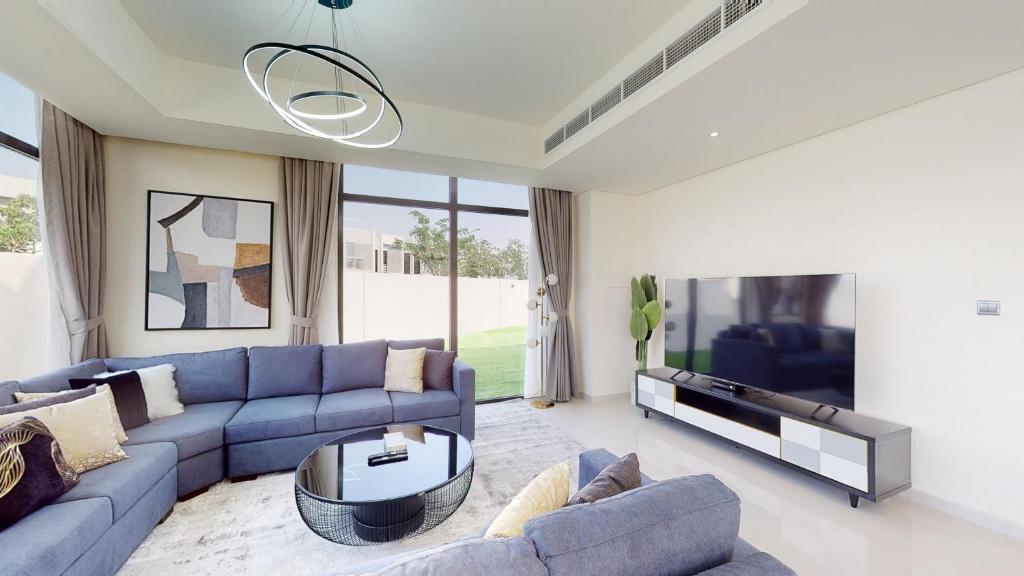a living room with a blue couch and a tv at Primestay - Odora 6BR, Akoya Oxygen in Dubai