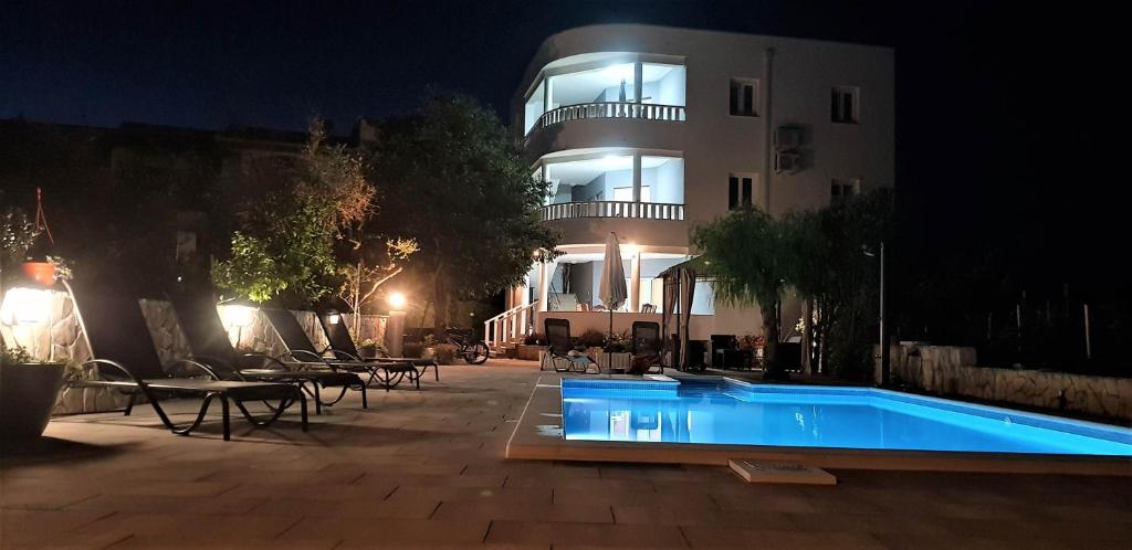 a swimming pool in front of a building at night at Villa Stella in Rogoznica