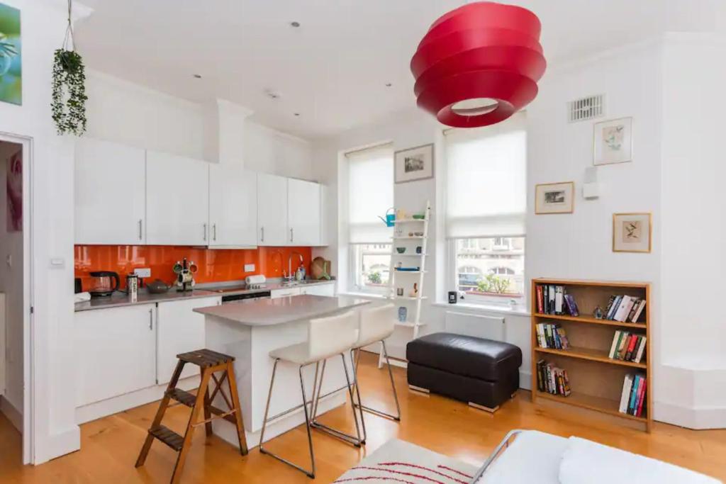 a kitchen with white cabinets and a red ceiling at Homely 1 Bedroom Apartment in the Heart of Vibrant Camden in London