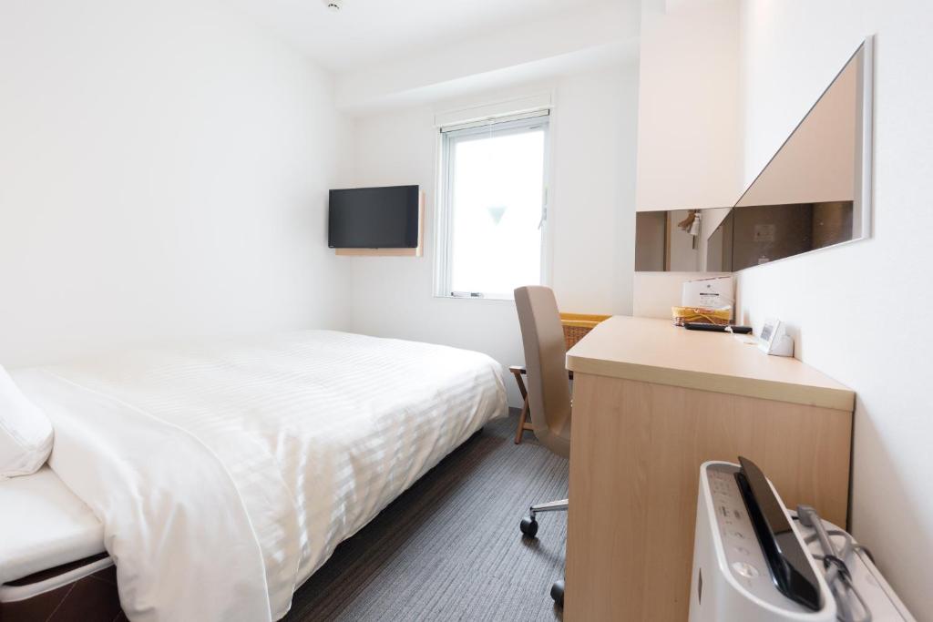 a bedroom with a bed and a desk with a computer at Super Hotel Tokyo Otsuka in Tokyo