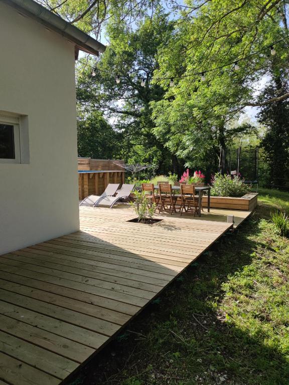 - une terrasse en bois avec des chaises et une table dans la cour dans l'établissement Adorable maison d'hôtes avec piscine- tiny house, à Saubrigues