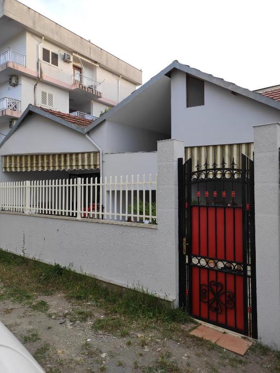 una casa blanca con una puerta roja y un edificio en Klea Rooms, en Velipojë