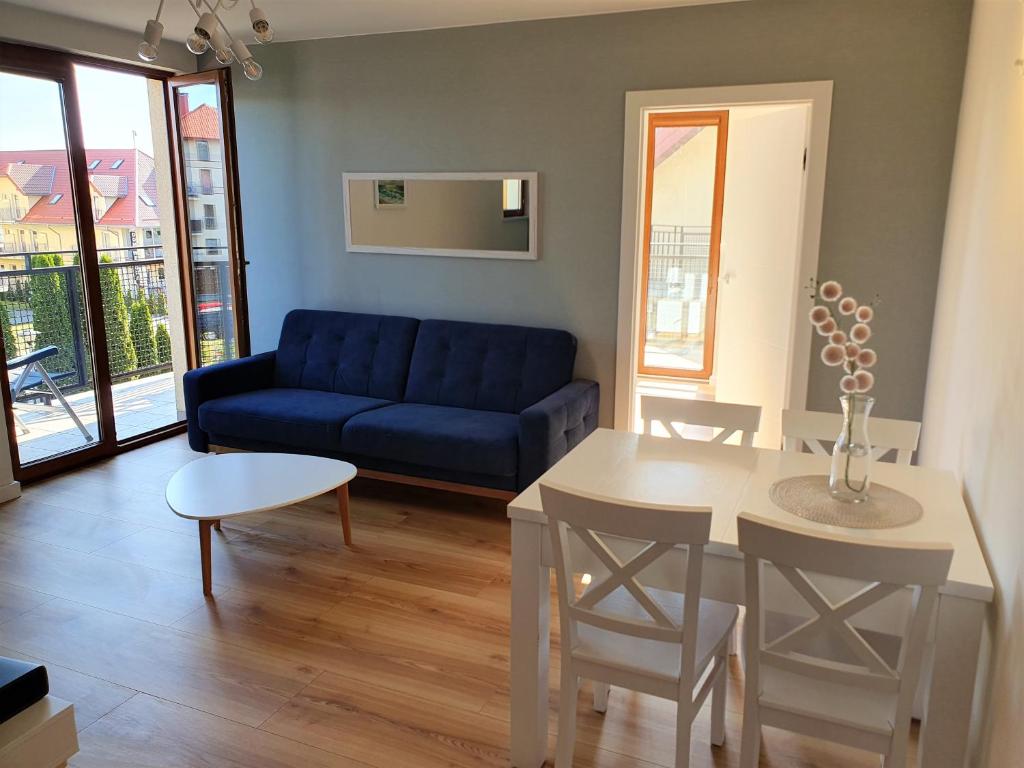 a living room with a blue couch and a table at APARTAMENT QUEEN KARWIA in Karwia