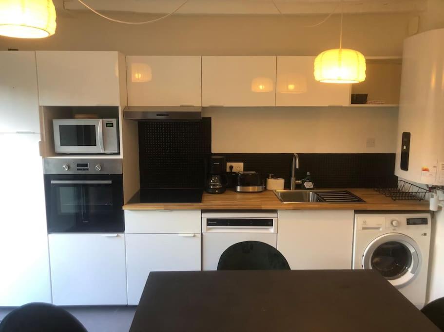 a kitchen with white cabinets and a sink and a table at Le 20 Les Terrasses. Maison de bord de Loire in Chalonnes-sur-Loire