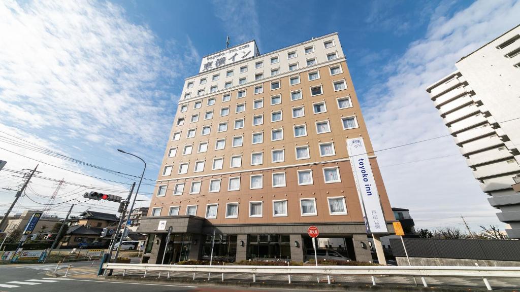 un grand bâtiment avec une horloge en haut dans l'établissement Toyoko Inn Saitama Toda koen eki Nishi guchi, à Toda