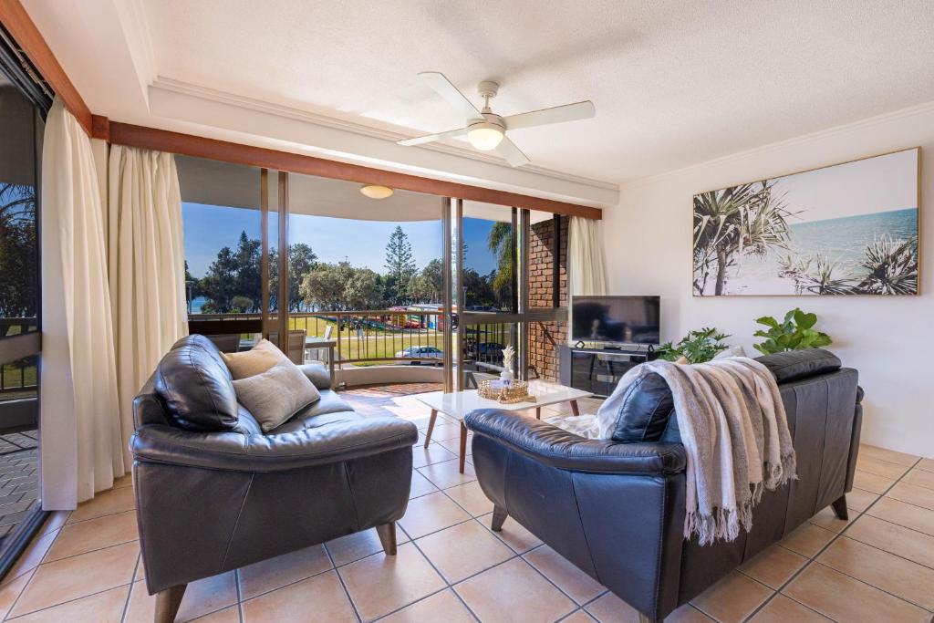 a living room with two leather chairs and a television at Coastal SOL -Right on Clarkes Beach! in Byron Bay