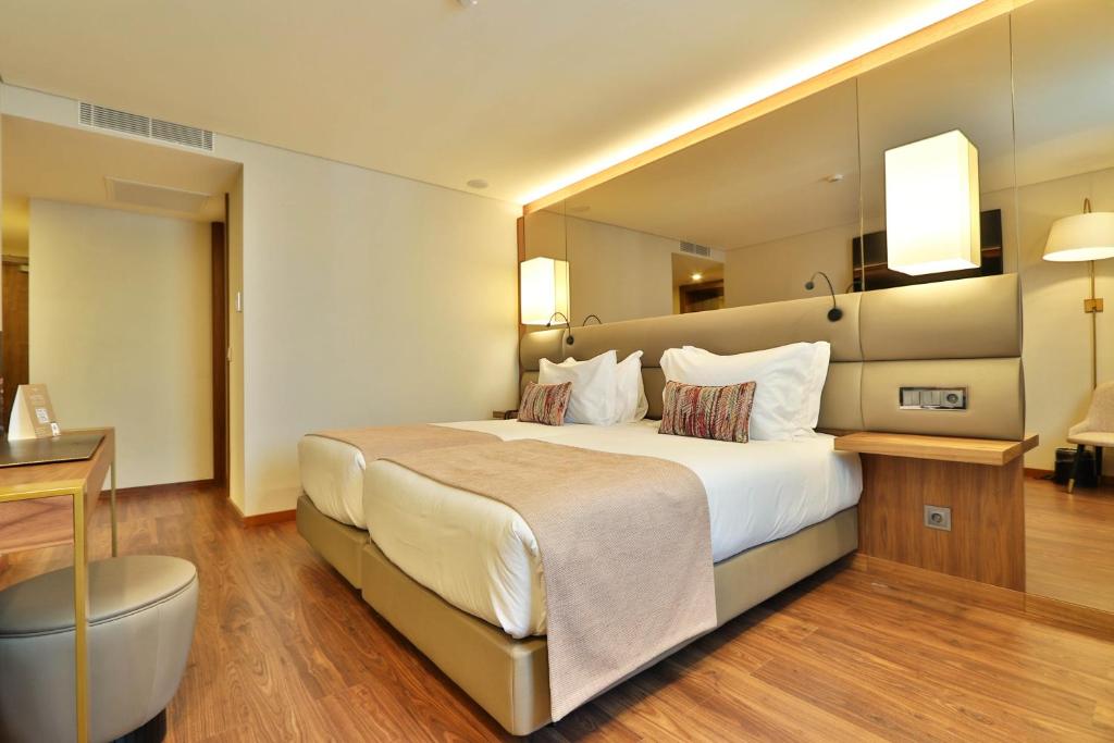 a hotel room with a large bed and a desk at TURIM Ibéria Hotel in Lisbon