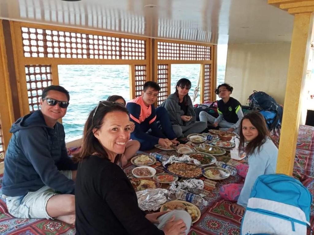eine Gruppe von Menschen, die an einem Tisch mit Essen sitzen in der Unterkunft Sailing boat in Assuan