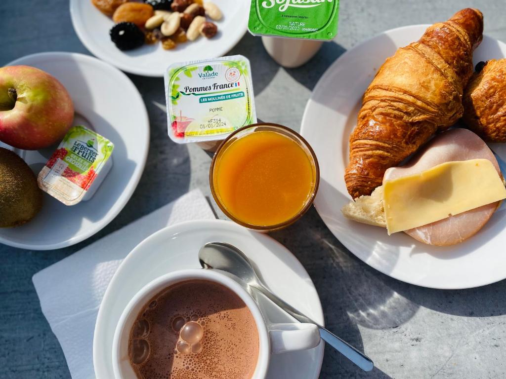 a table with plates of breakfast foods and a cup of coffee at Hôtel Le Belvedere in Saint-Cyprien