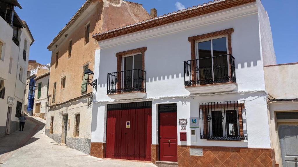 - un bâtiment blanc avec des portes rouges dans une rue dans l'établissement Casa Moraleda I Vivienda Rural, à Pinos del Valle