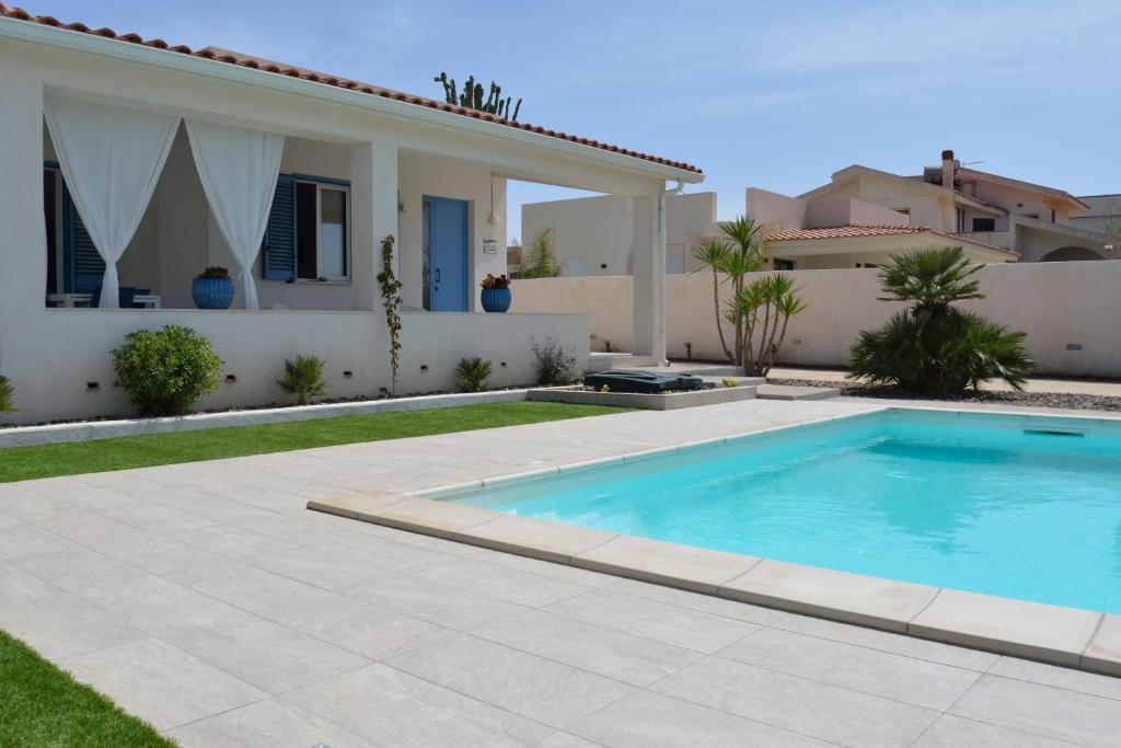 a villa with a swimming pool in front of a house at Villa Colapesce in Marzamemi