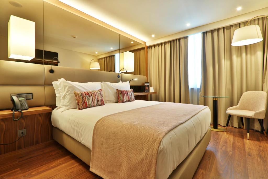a bedroom with a large bed and a chair at TURIM Ibéria Hotel in Lisbon