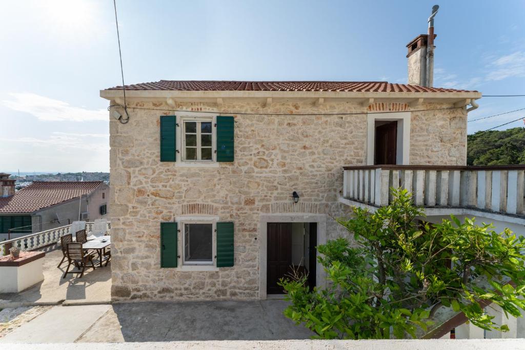 ein Steinhaus mit grünen Rollläden und einem Balkon in der Unterkunft Stonehouse Mali Lukoran in Lukoran