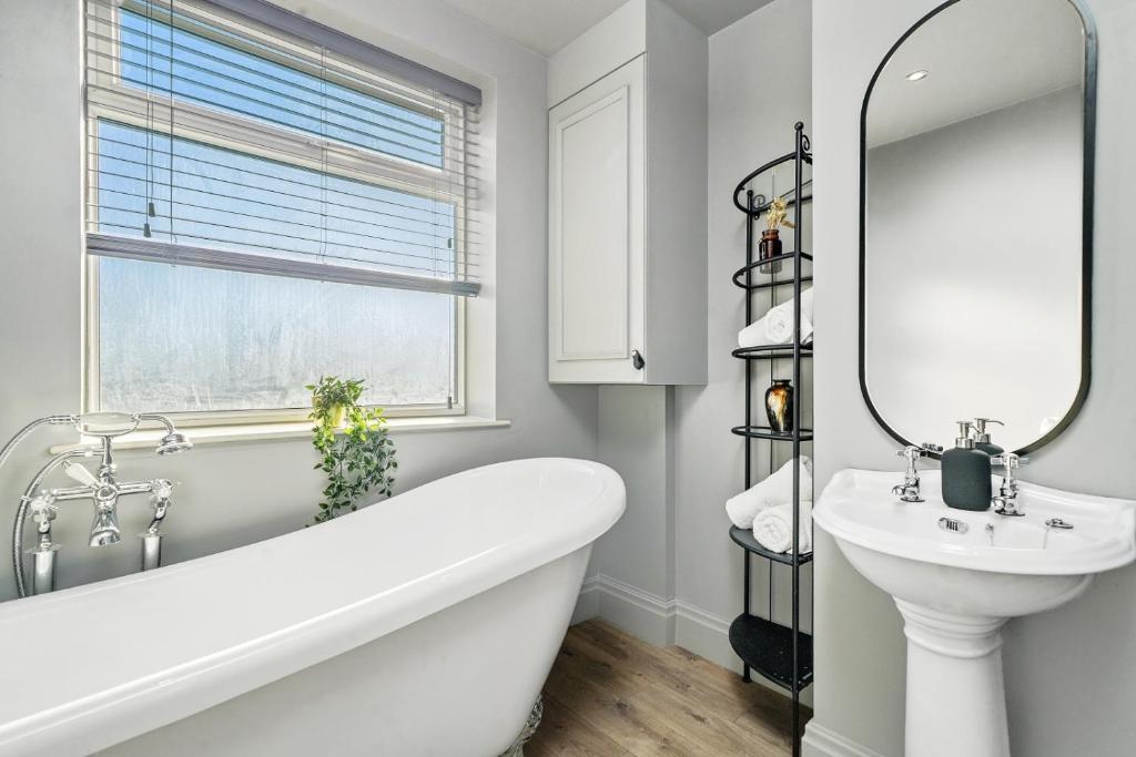 uma casa de banho com uma banheira, um lavatório e um espelho. em A selection of apartments in Golborne Business and Leisure WIFI Parking by Stone Pit Apartments em Golborne
