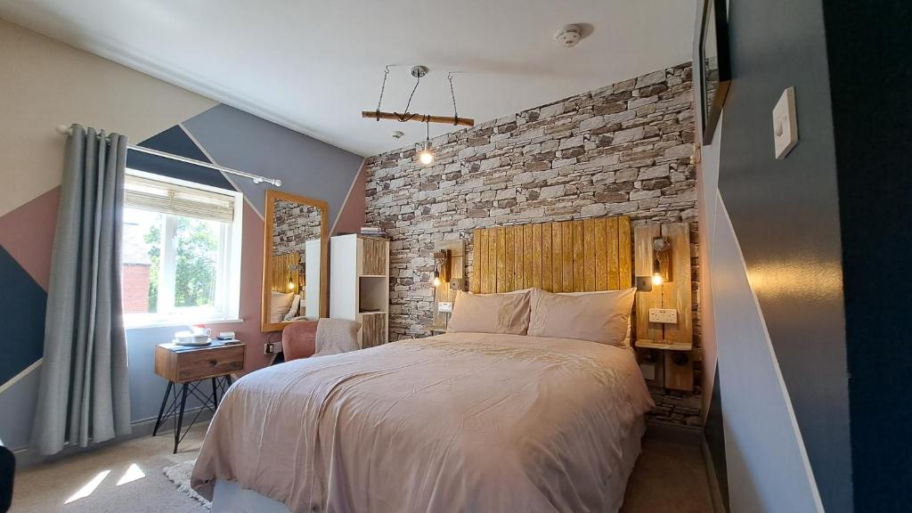 ein Schlafzimmer mit einem großen Bett und einer Ziegelwand in der Unterkunft Willow Studio in Telford