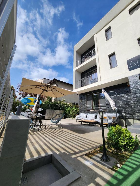 a building with a patio with chairs and an umbrella at Analeya in Eforie Nord