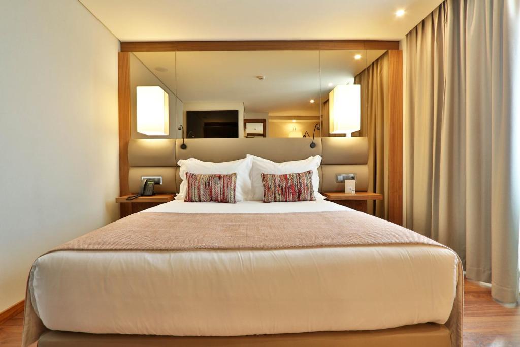a bedroom with a large bed with a large mirror at TURIM Ibéria Hotel in Lisbon