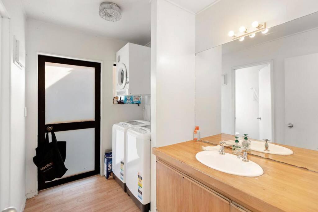 W łazience znajduje się umywalka, lustro i lodówka. w obiekcie Small Wallet-Friendly Private Room in a 7 BR Shared House - The Ben's Room 6 w mieście Queenstown