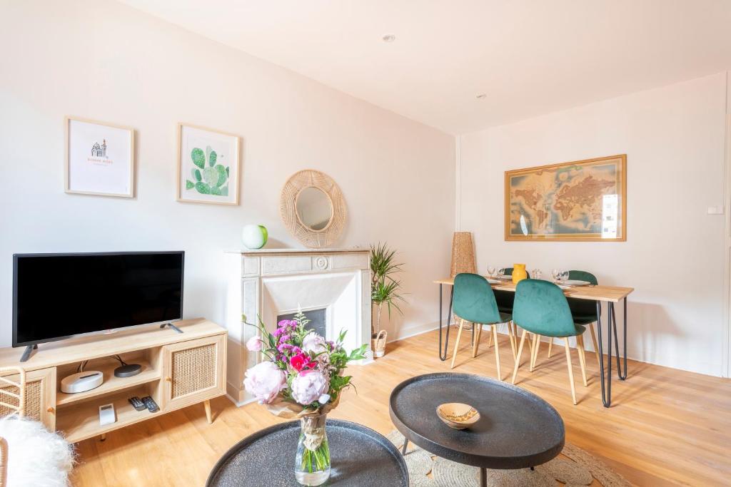 un salon avec une télévision et une table avec des chaises dans l'établissement Le Funiculaire - au pied de Notre Dame de la Garde, à Marseille