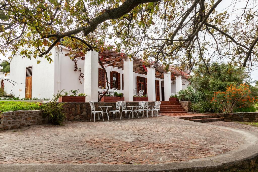 un patio frente a una casa blanca con sillas en Ayama Manor House, en Wellington