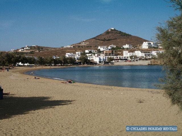 a beach with buildings and a mountain in the background at Afroditi studios in Kampos Paros