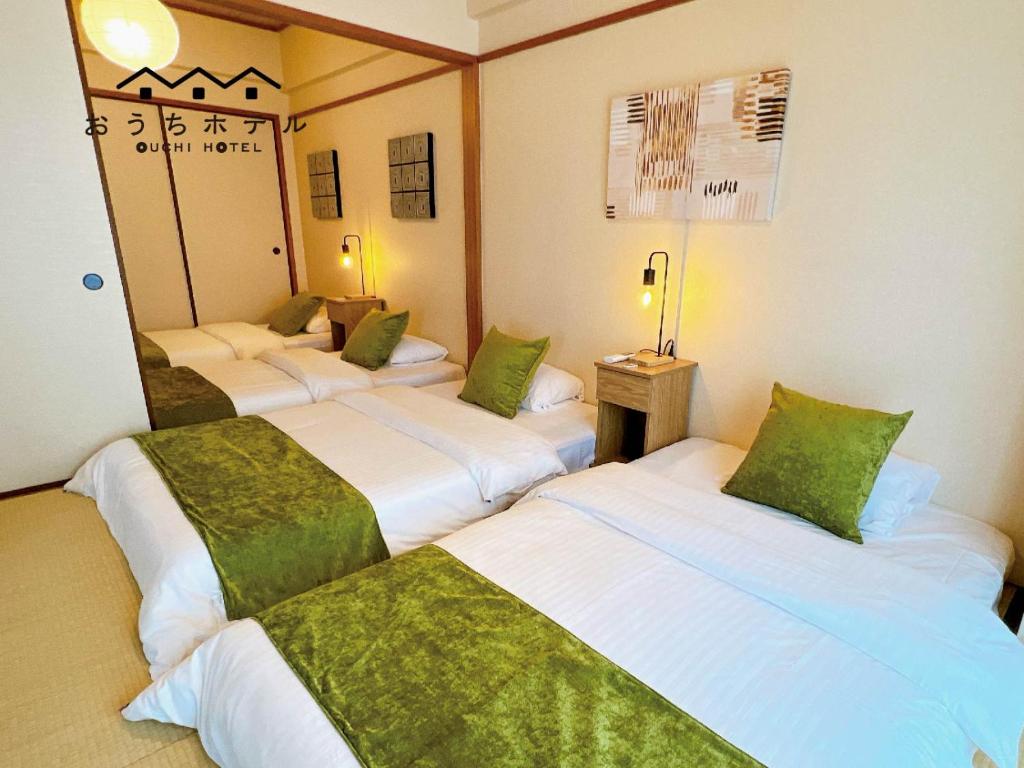 a hotel room with three beds with green pillows at OUCHI HOTEL Dambara in Hiroshima