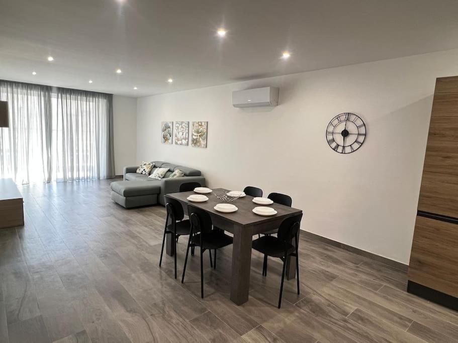 a living room with a table and chairs and a couch at Zejtun 3-Bedroom Modern Apartment in Żejtun