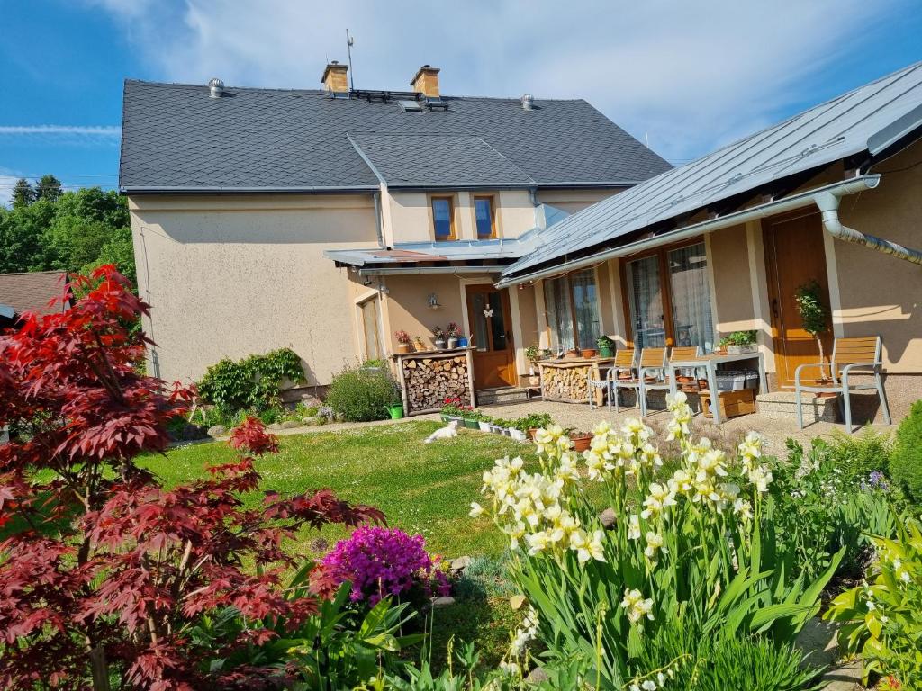 a house with a garden with flowers in the yard at Penzion U našich in Mladé Buky