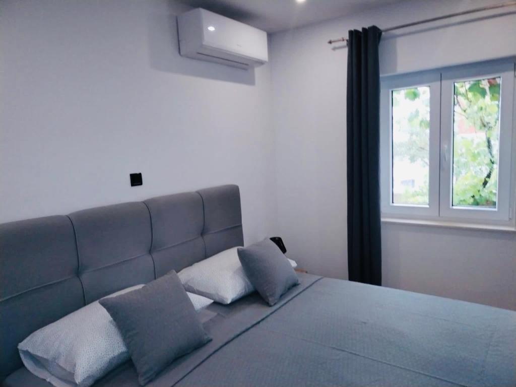 een slaapkamer met een bed met 2 kussens en een raam bij Apartment Aurora in Hvar