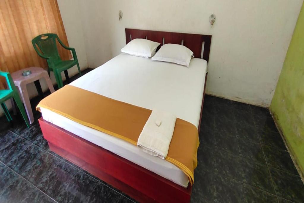 Cette chambre comprend un grand lit et 2 chaises vertes. dans l'établissement SPOT ON 92648 Wisma Padi Syariah Panyipatan, 