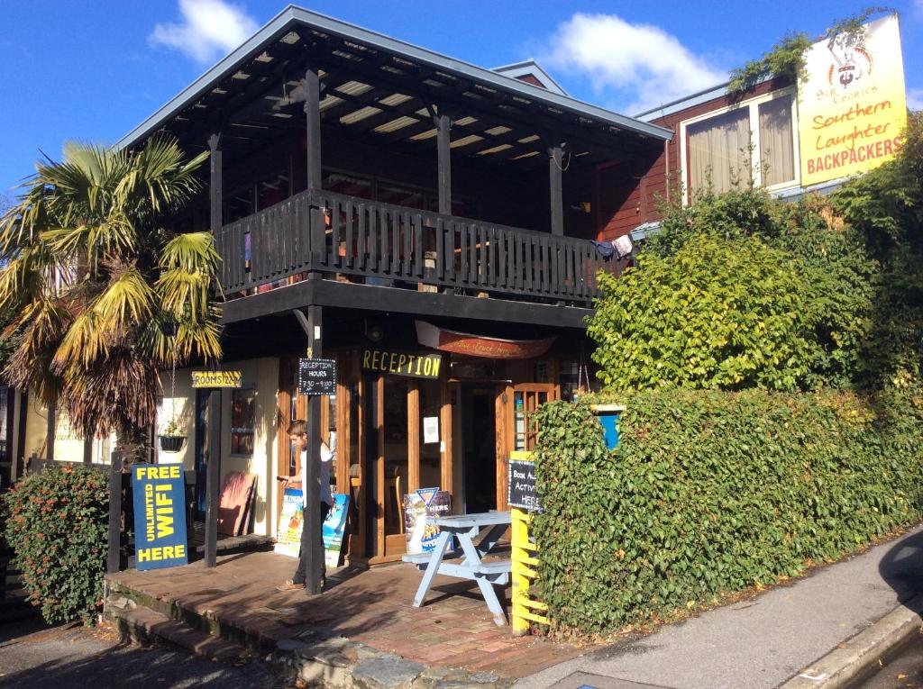 a building with a balcony and a table in front of it at Southern Laughter Backpackers in Queenstown