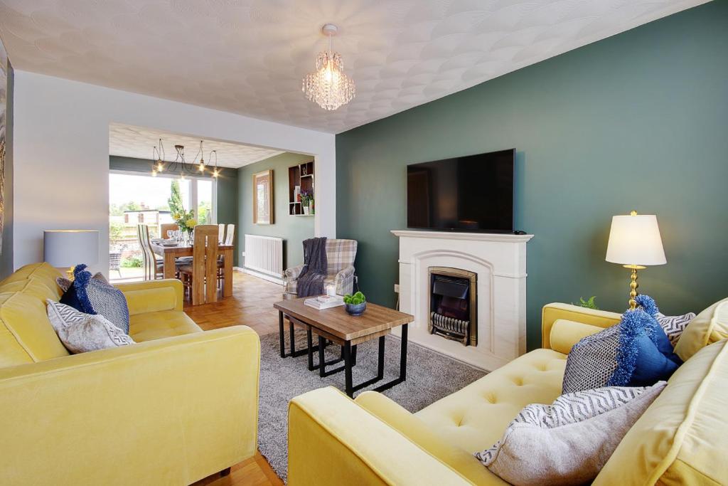 a living room with two yellow couches and a fireplace at Lyndhurst Forest Edge - Sleeps 6 in Lyndhurst