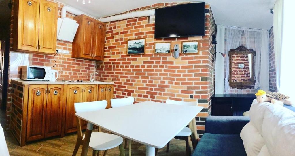 a kitchen with a white table and a brick wall at Zolotoi Bereg 31 in Odesa