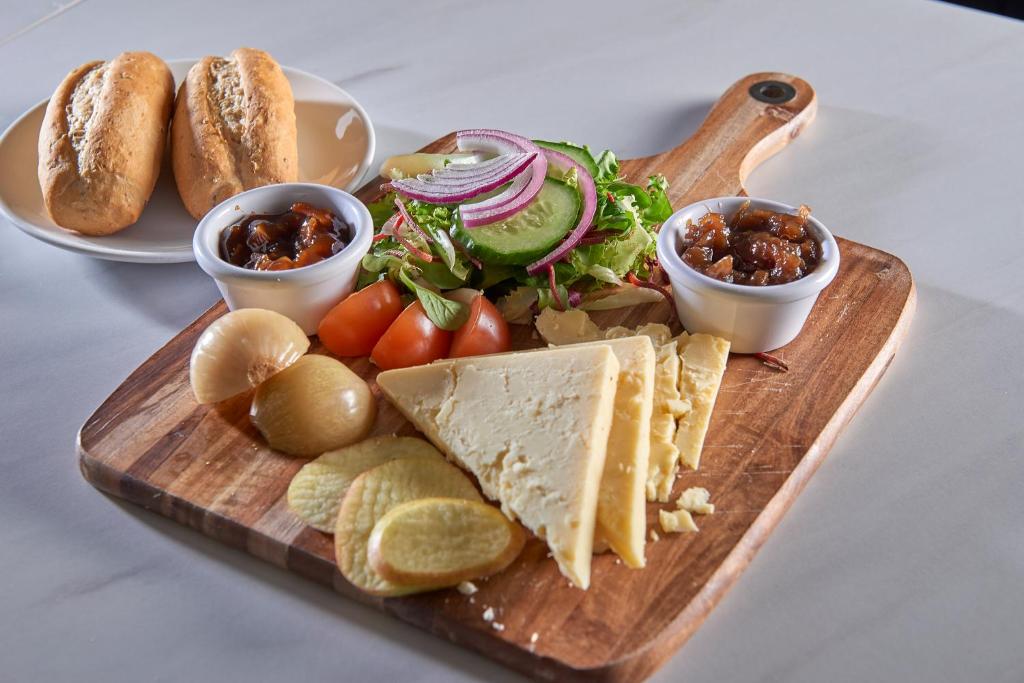 a cutting board with a sandwich and salad and dips at The Crown Hotel in Weymouth