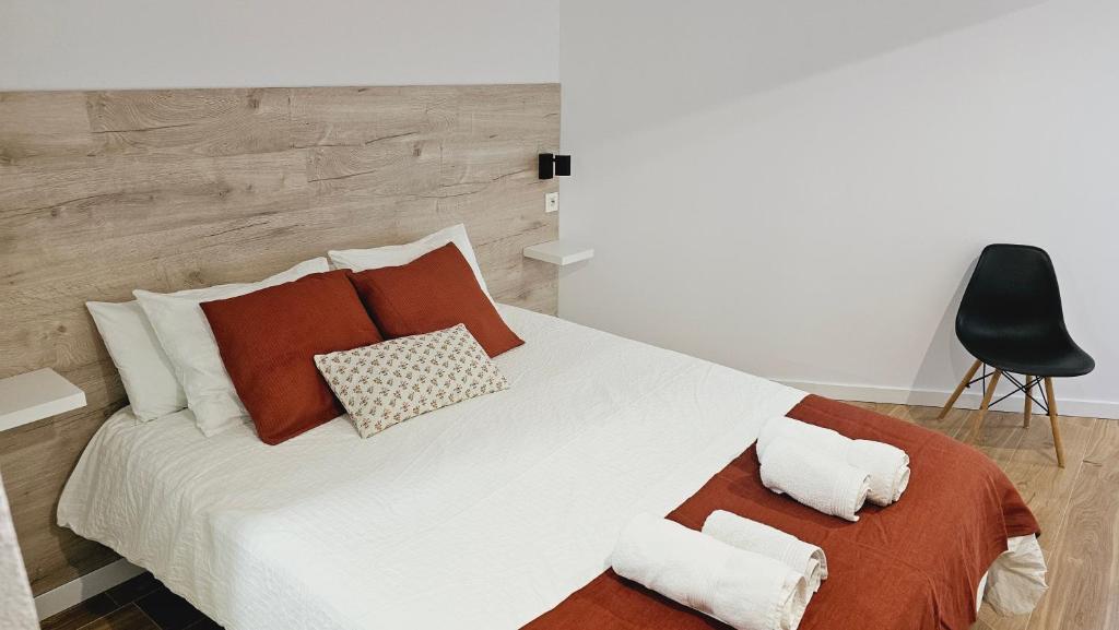 een slaapkamer met een groot wit bed met kussens en een stoel bij Apartamento Noray Bermeo in Bermeo