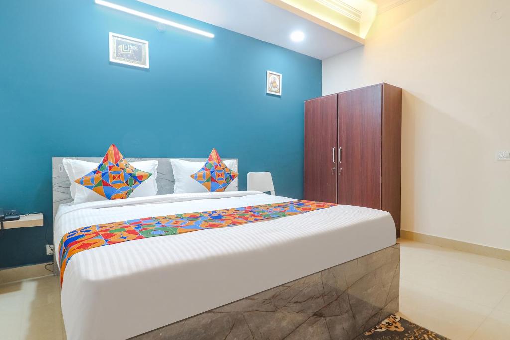 1 dormitorio con 1 cama grande y pared azul en FabHotel Broholic Suites I en Hyderabad