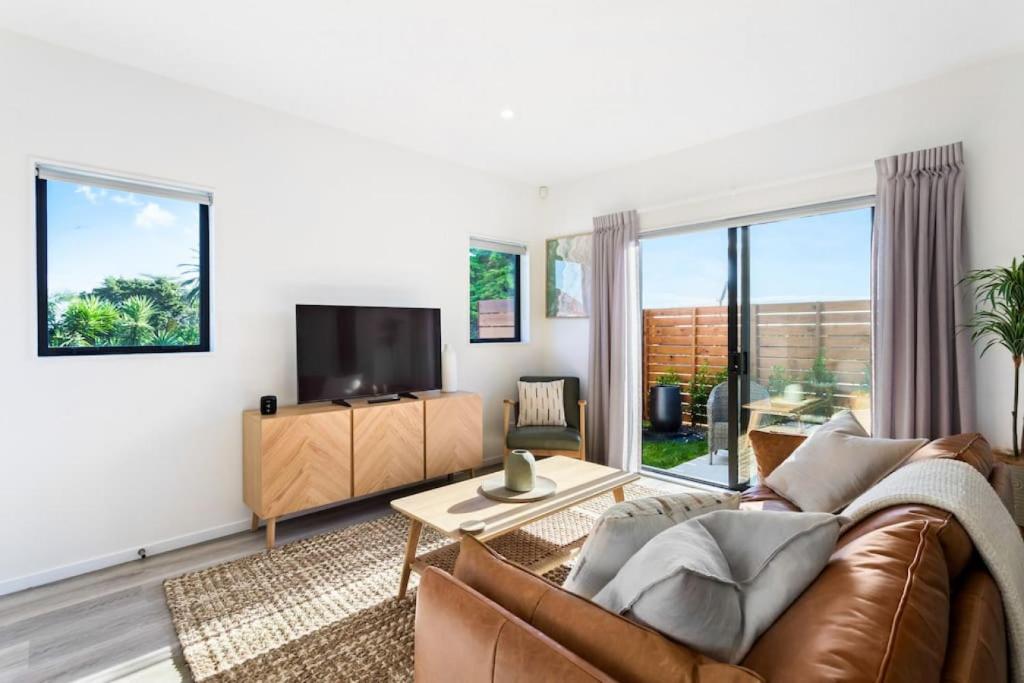 ein Wohnzimmer mit einem Sofa und einem TV in der Unterkunft Stunning New 2BR Luxury in Pukekohe - WiFi Netflix in Pukekohe East