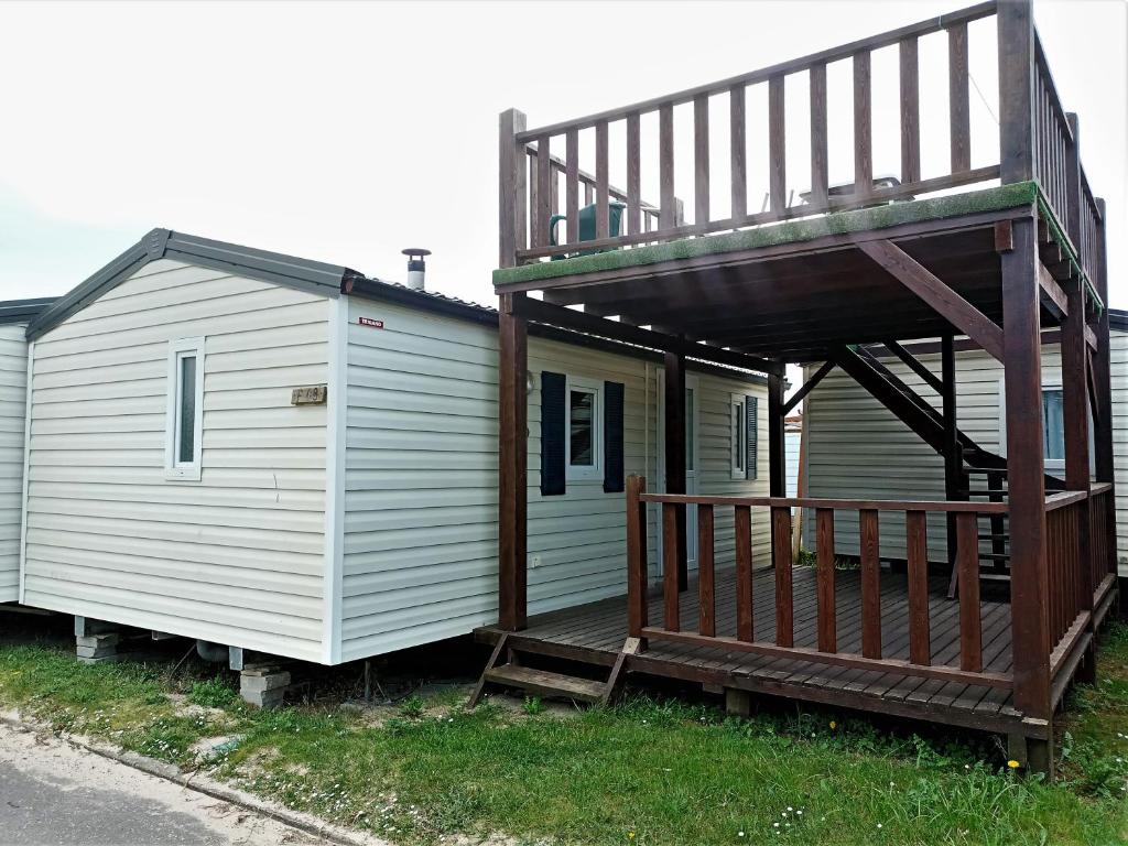 uma pequena casa branca com um alpendre e um deque em Camping Derby Loredo em Loredo