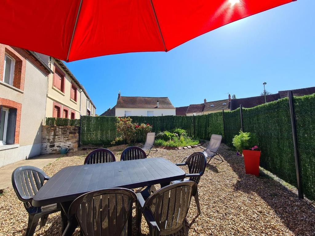 a black table and chairs with a red umbrella at L'EssenCiel du Lac in Éguzon-Chantôme