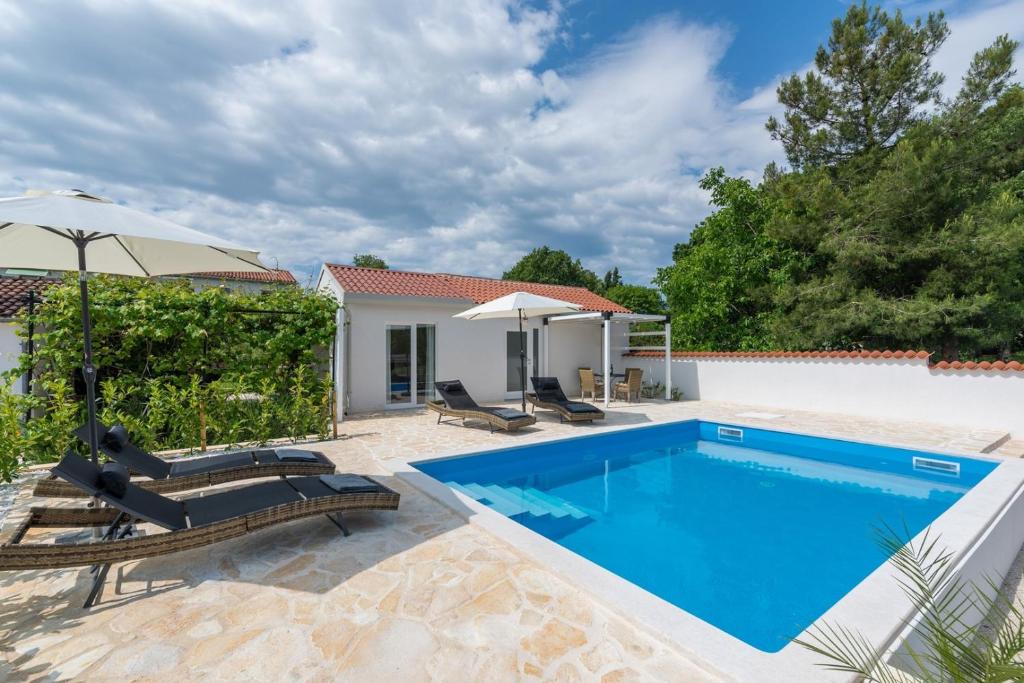 una piscina con sillas y una sombrilla junto a una casa en Casa Cosini with Private Pool, en Poreč