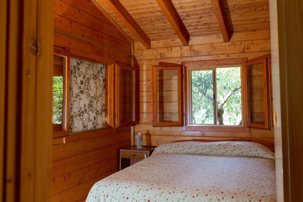 een slaapkamer met een bed in een houten hut bij CHALET TRA GLI ULIVI: • giardino • WiFi • A/C • bbq in Capri Leone